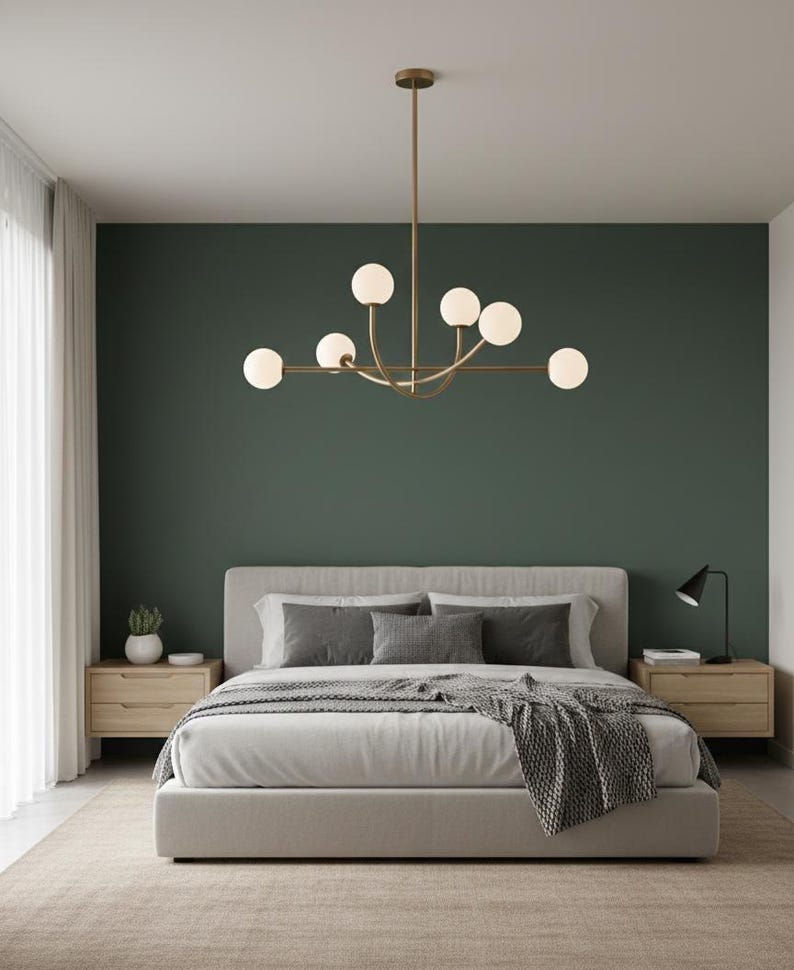 Pu&ograve; includere: Una camera da letto moderna con un letto con lenzuola e cuscini grigi, comodini in legno e un lampadario dorato con luci sferiche. La parete &egrave; dipinta di verde scuro e la stanza ha un design minimalista.