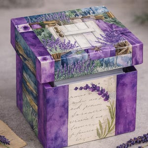 May include: A decorative box with a watercolor design featuring lavender and a white door. The box is primarily purple with accents of green and blue. The box has a hinged lid and a floral design on the front.