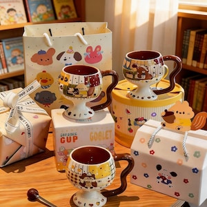 Puede incluir: Una taza de cerámica blanca con asa negra y el texto "But First, Coffee" en negrita negra. La taza se encuentra sobre un fondo neutro, resaltando su diseño sencillo.