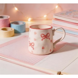 May include: A set of three ceramic mugs with a speckled, matte finish. The mugs are in shades of cream, light grey, and dark grey. Each mug has a simple, minimalist design and a rounded handle. Ideal for tea or coffee.