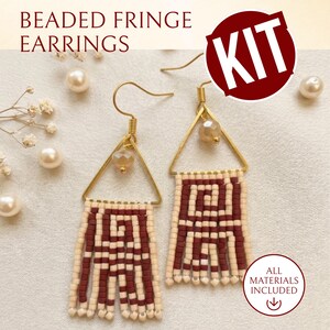 May include: A pair of beaded fringe earrings with a geometric design in cream and burgundy. The earrings have gold-colored triangle frames and gold-colored ear wires. The image includes the text "BEADED FRINGE EARRINGS" and a kit label.