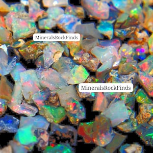 May include: A close-up shot of a collection of raw opal gemstones. The opals exhibit a range of colours, including blue, green, red, and yellow, with iridescent flashes. The text "MineralsRockFinds" is visible on the image.