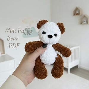 Può includere: Un mini orsetto soffice fatto a mano, con corpo bianco e braccia, gambe e orecchie marroni. L'orso ha occhi neri e naso nero. Il testo "Mini Puffy Bear PDF" è nell'immagine. È un giocattolo di peluche morbido.