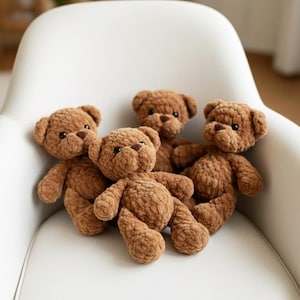 Könnte beinhalten: Vier handgefertigte braune Teddybären mit dunkelbraunen Augen und Nasen sind auf einem weißen Stuhl angeordnet. Die Bären haben ein weiches, strukturiertes Aussehen mit sichtbaren Nähten und Plüschmaterial. Die Bären sind ein klassisches Spielzeug.