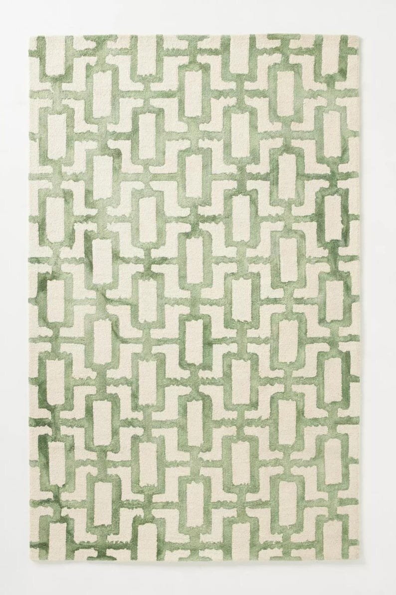 May include: Rectangular rug with a repeating geometric pattern in shades of green on a cream background. The design features interconnected rectangles, creating a modern look. Suitable for living rooms, bedrooms, or hallways. The rug measures approximately 150 cm x 200 cm.