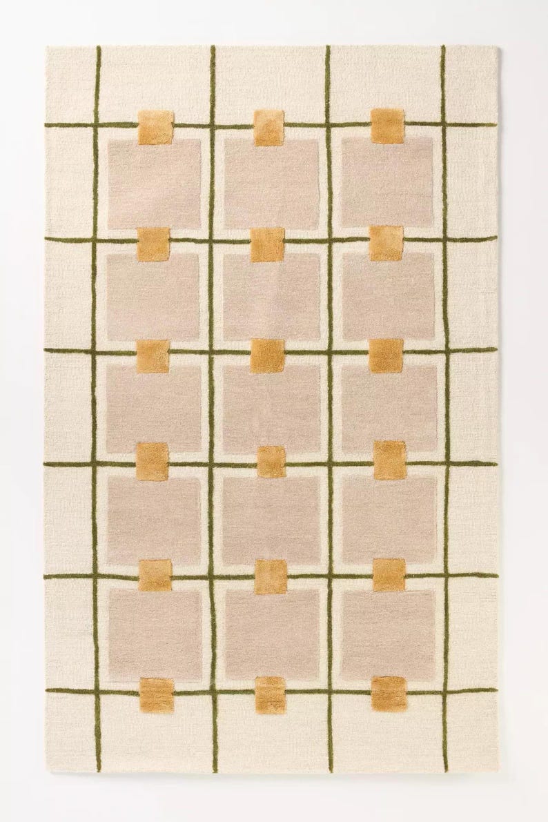 Puede incluir: Una alfombra rectangular con un dise&ntilde;o de cuadr&iacute;cula. La alfombra tiene un fondo color crema con una cuadr&iacute;cula verde oliva oscuro. Cuadrados de color rosa claro se intercalan dentro de la cuadr&iacute;cula, con peque&ntilde;os cuadrados de color mostaza en las intersecciones.