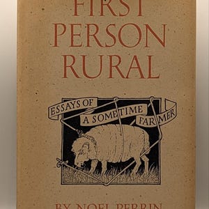 May include: A tan hardcover book titled First Person Rural, Essays of a Sometime Farmer by Noel Perrin. The cover features a black and white illustration of a sheep inside a wire fence enclosure, with the title and author name in red text.