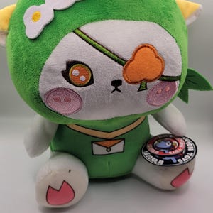 May include: A white ceramic mug with a black handle and the text "But First, Coffee" in a handwritten style. The mug is on a white surface. The mug is approximately 10 cm tall.