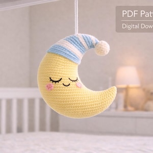 May include: A crocheted yellow crescent moon with a blue and white striped cap and a white pom-pom. The moon has closed eyes and pink cheeks. The image includes the text "PDF Pattern Digital Download".