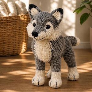 Könnte beinhalten: Ein handgefertigtes Wolfsspielzeug aus Häkelarbeit in Grau-, Weiß- und Schwarztönen. Der Wolf hat eine flauschige cremefarbene Brust und eine schwarze Nase. Das Spielzeug steht auf vier Beinen, mit weißen Pfoten und einem kleinen Schwanz.