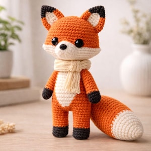 Puede incluir: Muñeco de zorro tejido a ganchillo con hilo naranja y blanco, ojos negros y bufanda color crema. El zorro tiene una cola larga y detalles negros en las patas y orejas. El texto de la imagen dice "PDF Pattern Digital Download."