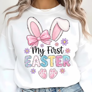 May include: White sweatshirt with a colorful "My First Easter" design. The design includes bunny ears, a pink bow, flowers, and paw prints. The letters in "EASTER" are pastel colors.
