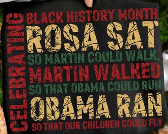 May include: Black t-shirt with text celebrating Black History Month. The text reads "ROSA SAT SO MARTIN COULD WALK, MARTIN WALKED SO THAT OBAMA COULD RUN, OBAMA RAN SO THAT OUR CHILDREN COULD FLY."