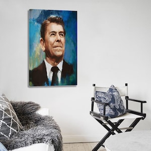K&ouml;nnte beinhalten: Ein Gem&auml;lde eines Mannes in Anzug und Krawatte vor blau-gr&uuml;nem Hintergrund. Das Kunstwerk h&auml;ngt an einer wei&szlig;en Wand. Ein Regiestuhl und ein dekoratives Kissen befinden sich im Vordergrund.