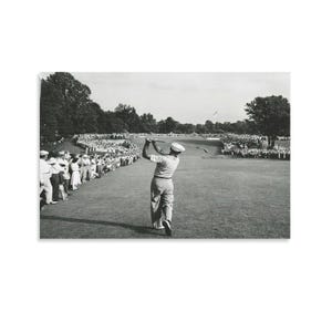 Puede incluir: Fotografía en blanco y negro de un golfista en pleno swing en un campo de golf. El golfista lleva gorra y ropa clara. Los espectadores bordean la calle y rodean el green, observando el juego.