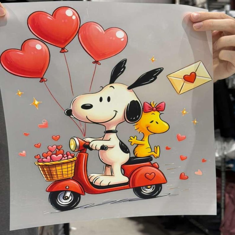 May include: A white cartoon dog with black ears and a yellow bird with a pink bow riding a red scooter. The dog holds three red heart-shaped balloons, and the scooter basket is filled with small red hearts. A yellow envelope with a red heart is nearby.