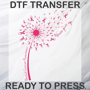 May include: A DTF transfer ready to press featuring a pink dandelion graphic where the seeds are small breast cancer awareness ribbons. The stem reads Breast Cancer Awareness and the text Never give up is written in a cursive script to the right.