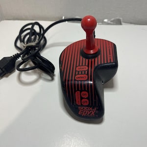 May include: Black and red Epyx 500XJ joystick controller with a red joystick and buttons for start, select, on, and off. The controller has a black cable and connector.