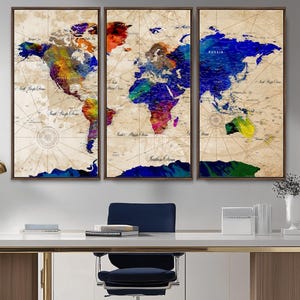 May include: A set of three framed world map prints. The maps feature a vintage style with a beige background and colorful watercolor-style continents. The frames are a dark brown color. The maps are displayed on a white desk.