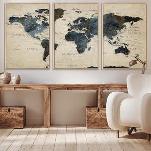 May include: Three framed world map prints. The maps feature a vintage aesthetic with a beige background and blue and brown watercolor-style continents. The frames are a light brown color. The prints are displayed above a wooden console table.