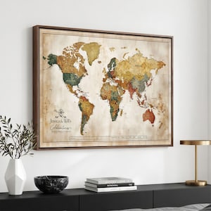 May include: A rectangular framed world map wall art piece with a vintage-style parchment background. The map features muted earth tones, including shades of brown, green, and tan. The text "Jessica & Will's Adventures" is printed on the left side.