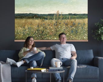 May include: A large rectangular wall art print featuring a landscape painting of a wildflower meadow under a pale sky, mounted in a light wood frame. The artwork displays a field of yellow, white, and blue flowers with a dark green treeline.