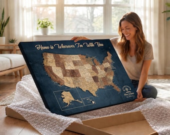 May include: A rectangular wall art canvas featuring a map of the United States in shades of brown against a dark blue background. The text Home is Wherever I'm With You is printed in gold at the top, with Chris & Emma below a compass icon.