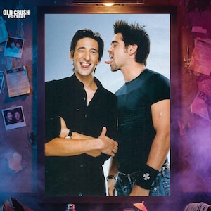May include: A framed poster featuring two men, one sticking out his tongue at the other. The poster is in a dimly lit room with the words "OLD CRUSH POSTERS" in the upper left corner. The room has a bar-like setting.