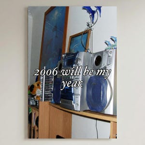 Könnte beinhalten: Eine silberne Stereoanlage mit blauen Akzenten und Lautsprechern steht auf einem Holzregal. Der Text "2006 will be my year" ist auf dem Bild überlagert. Ein gerahmtes Bild und Delfindekorationen sind ebenfalls zu sehen.