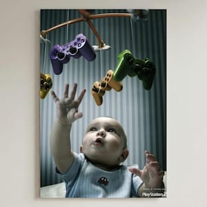 May include: A baby reaching for a mobile of colorful PlayStation 2 controllers. The controllers are purple, green, yellow, and gold. The background is a blue and white striped wall. The image has the text "FROM 10 YEARS ON PlayStation 2".