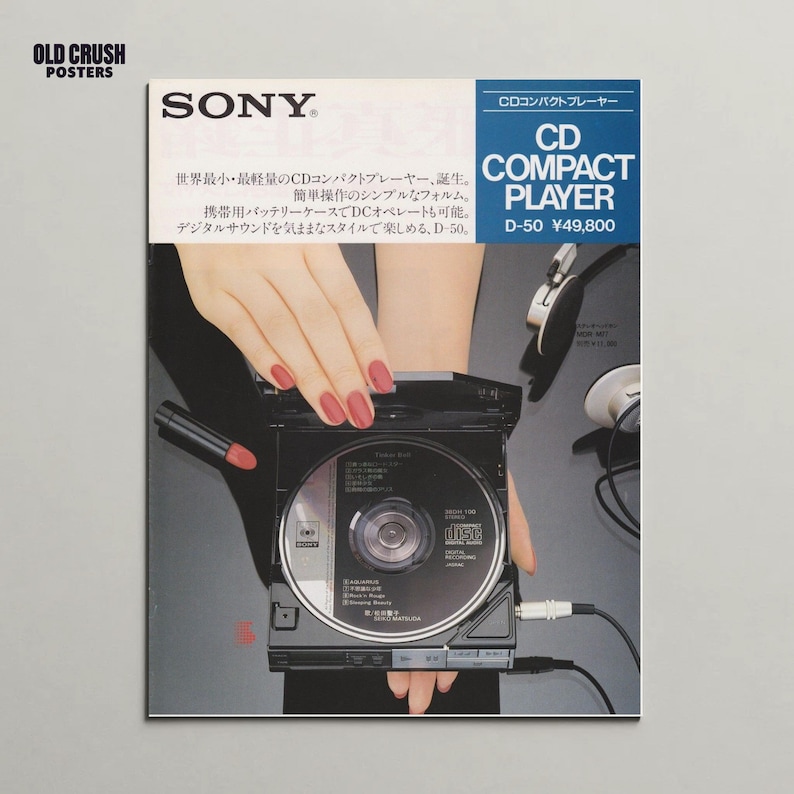 Op de afbeelding: Vintage advertentie voor een Sony CD Compact Player. De afbeelding toont een zwarte cd-speler met een schijf erin, vastgehouden door een persoon met rode nagellak. De advertentie bevat Japanse tekst en het Sony-logo.