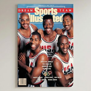 May include: A framed magazine cover featuring five smiling basketball players in USA jerseys. The cover reads "Dream Sports Illustrated Team" with the date February 18, 1991. Text includes "Watch out, world! This could be America's 1992 Olympic Five."