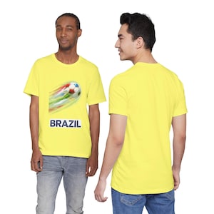 Puede incluir: Dos personas con camisetas amarillas. Una camiseta tiene un balón de fútbol con rayas de colores y la palabra "BRAZIL" en azul marino. La otra camiseta es amarilla lisa. Ambos llevan vaqueros azules.
