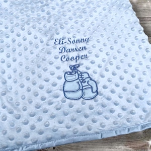 Può includere: Coperta per neonati azzurra con superficie a pois. La coperta presenta il ricamo "Eli-Sonny Darren Cooper" sopra un paio di guantoni da boxe. La coperta ha un bordo in raso.