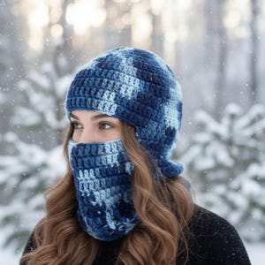 May include: A blue and white crocheted winter hat and face covering set. The hat has ear flaps and the face covering covers the nose and mouth. The set is made of a soft, textured yarn and is suitable for cold weather.
