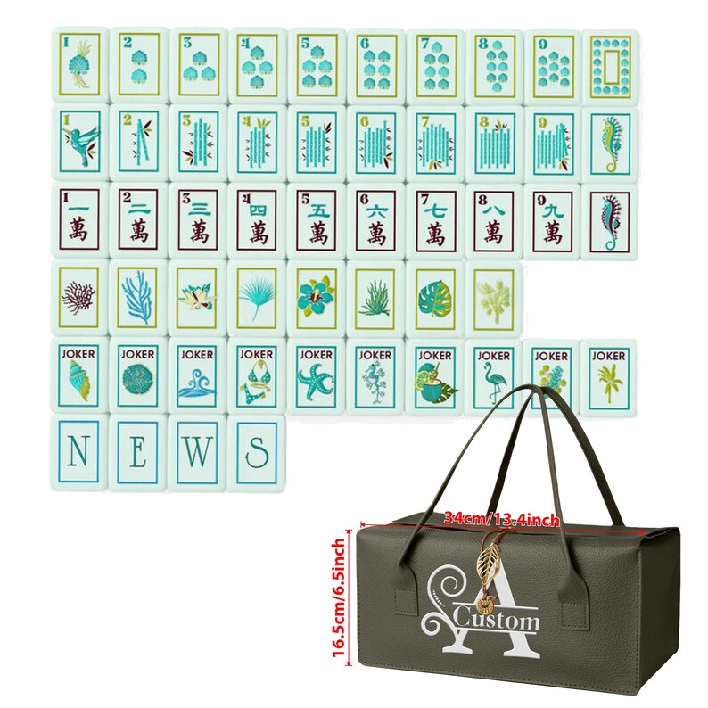 Puede incluir: Un juego de fichas de Mahjong blancas con ilustraciones azules y verdes de vida marina, plantas y n&uacute;meros, junto a una bolsa de almacenamiento rectangular verde oscuro con un dije de hoja dorada y el texto Custom, que mide 34cm por 16,5cm.