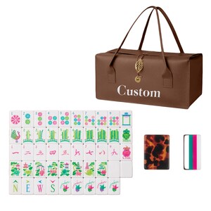 May include: A brown rectangular carrying bag with the word Custom printed in white, featuring a gold leaf charm. Below are white mahjong tiles with colorful floral, bamboo, and character designs, alongside two additional tiles with tortoise and striped patterns.