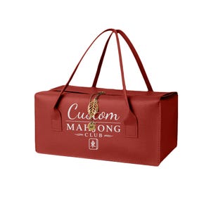 May include: A rectangular red textured bag with two thin handles. The front features white text reading Custom MAHJONG CLUB above a small square icon with the character 東. A gold-colored metal leaf charm hangs from the top center closure.