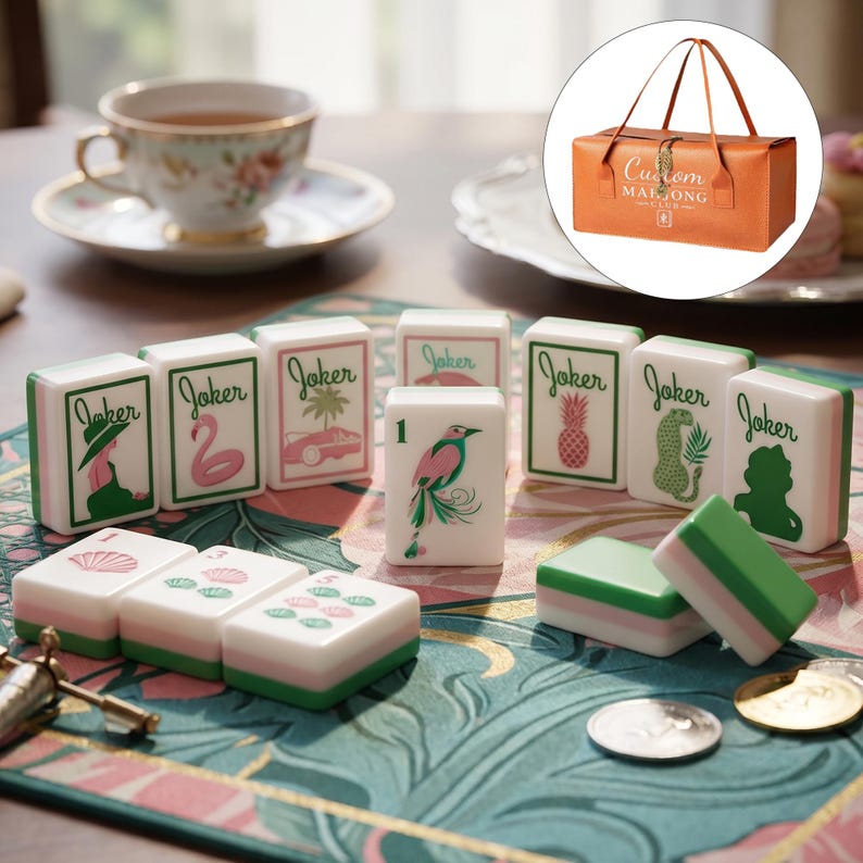 May include: A set of white mahjong tiles featuring green and pink illustrations of jokers, birds, and tropical motifs, accompanied by a rectangular orange carrying case with the text Custom Mahjong Club printed on the front surface.