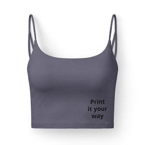 May include: A slate-gray crop top with thin spaghetti straps and a scoop neckline. The text "Print it your way" is printed in black on the lower right side of the top. The top is made of a smooth, solid fabric.