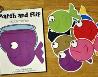 May include: A "Match and Flip Match the Fish" game with a purple fishbowl illustration and colorful fish cutouts. The game includes a booklet and several fish-shaped cards in various colors, including green, red, and pink. The game is on a wooden surface.