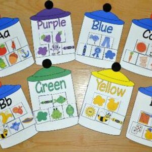 May include: Eight educational cards shaped like jars, each with a lid and a different colour. Each card displays a letter, a colour name, and associated images. The colours include purple, blue, green, and yellow.