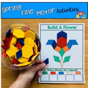 Può includere: Una ciotola trasparente piena di forme geometriche colorate e una mano che tiene una forma a diamante blu. Una scheda bianca mostra un fiore fatto di forme simili con il testo "Build A Flower" e "How Many Blocks Do I Need?" L'immagine è etichettata "Spring Fine Motor Activities."