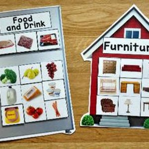 以下が含まれることがあります： 「Food and Drink」のラベルと食品の画像が付いた冷蔵庫型のマグネット。 「Furniture」のラベルと家具の画像が付いた家型のマグネット。どちらも木製の表面にあります。