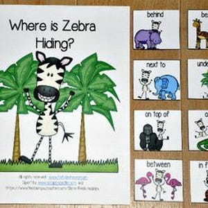 May include: A children's book titled "Where is Zebra Hiding?" with a zebra illustration and accompanying cards showing prepositions like "behind" and "beside." The book and cards are on a wooden surface.