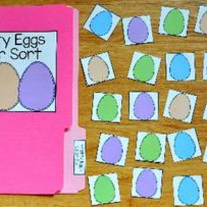 May include: A pink file folder with the text "Pretty Eggs Color Sort" and images of blue, tan, and purple eggs. Scattered around are matching egg-shaped cards in various colors, perfect for a color sorting activity.