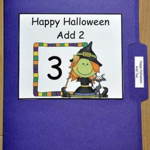 May include: A purple file folder with a white label that reads "Happy Halloween Add 2." The label features a cartoon witch holding a broom and a black cat. The number "3" is inside a colorful frame.