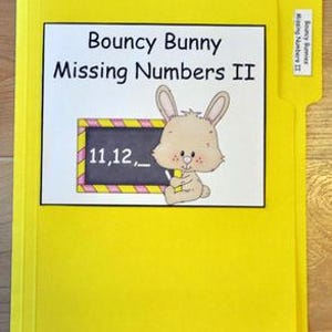 May include: A yellow file folder labeled "Bouncy Bunny Missing Numbers II." The folder features a cartoon bunny holding a pencil next to a chalkboard with the numbers 11, 12, and a blank space. The tab on the side also reads "Bouncy Bunny Missing Numbers II."