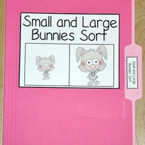 May include: A pink file folder with a white label that reads "Small and Large Bunnies Sort." The label features two cartoon bunnies, one small and one large. A smaller tab on the side repeats the title.