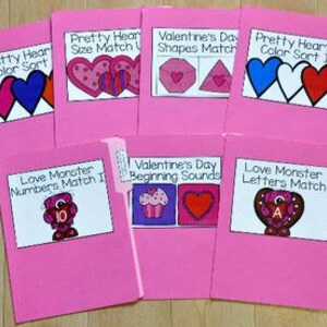 Puede incluir: Una colección de carpetas rosas con etiquetas blancas que presentan actividades educativas con temática de San Valentín. Los títulos incluyen "Pretty Hearts Color Sort", "Valentine's Day Shapes Match" y "Love Monster Numbers Match I."